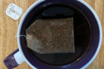 A cup of tea steeping in a white and purple mug.