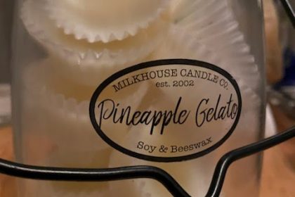 A butter jar with a black handle sits on a counter top, branded Milkhouse Candle Company, contains a batch of homemade wax melts.