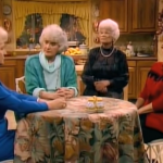A decorative image screenshot of an episode of The Golden Girls, with Betty White as Rose Nylund wearing a blue suit, Estelle Getty as Sophia Petrillo wearing a turquoise cardigan and a light blue sweater, Bea Arthur as Dorothy Zbornak wearing a black sweater and a gold necklace, Rue McClanahan as Blanche Deveraux wearing a red and black striped sweater, all sitting at the kitchen table, covered in a floral-print tablecloth.