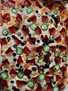 A close-up of a batch of Lunch Lady Pizza, made with Walmart house-brand gluten free flour, topped with a can of spaghetti sauce, mozzarella, turkey pepperoni, olives, serrano peppers, and jalapenos.