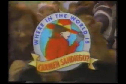 A screenshot from an episode of the PBS kids' geography game show, Where in the World is Carmen Sandiego?, depicting the title card with a cartoon rendering of Carmen Sandiego, a woman with brown hair, light skin, a red fedora hat, and a red trench coat in the middle of the show's circular logo. Children in the audience are shown in the background.