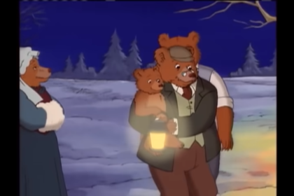 A screenshot from an episode of Little Bear, about their winter solstice celebration. Little Bear is in Grandpa Bear's arms, holding a lantern to hang on the tree for the snow angels. Grandma Bear is on the left hand side. Grandma Bear is wearing an 1890s dress and a bonnet. Grandpa Bear wears a dress shirt, tie, pants, and a vest in the style of the 1890s.