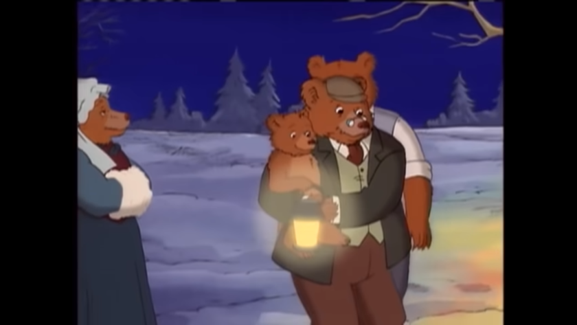 A screenshot from an episode of Little Bear, about their winter solstice celebration. Little Bear is in Grandpa Bear's arms, holding a lantern to hang on the tree for the snow angels. Grandma Bear is on the left hand side. Grandma Bear is wearing an 1890s dress and a bonnet. Grandpa Bear wears a dress shirt, tie, pants, and a vest in the style of the 1890s.