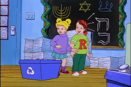 Screenshot from a holiday episode of The Magic School Bus, w/ Dorothy Ann and Ralph standing in front of a chalkboard decorated w/ menorahs and the Star of David. Dorothy Ann and Ralph are standing next to blue recycling bins.