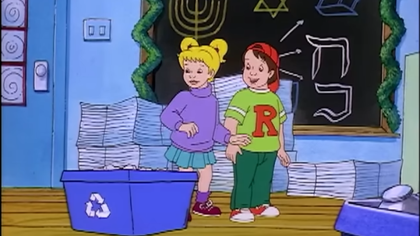 Screenshot from a holiday episode of The Magic School Bus, w/ Dorothy Ann and Ralph standing in front of a chalkboard decorated w/ menorahs and the Star of David. Dorothy Ann and Ralph are standing next to blue recycling bins.